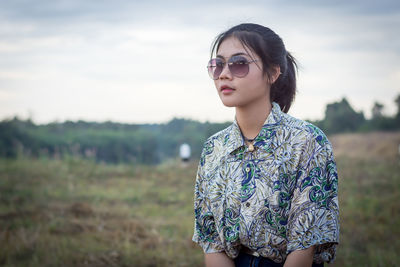 Young woman wearing sunglasses standing on field
