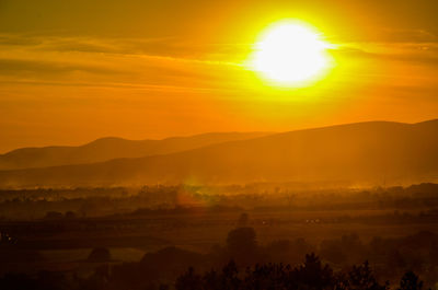Scenic view of silhouette mountains against orange sky