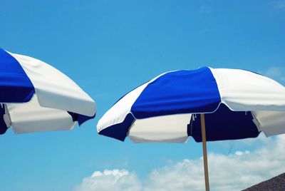 Low angle view of two vintage blue and white striped umbrellas against blue sky in california 