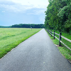 Road amidst field against sky