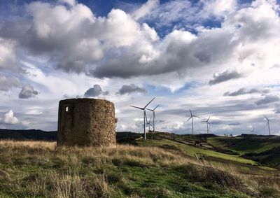 Windmills on field against sky