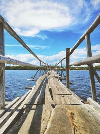 Human-made wooden bridge over sea against sky