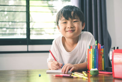 Portrait of boy sitting on table at home