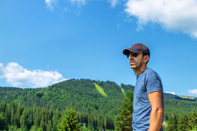Young man wearing sunglasses while standing against mountain