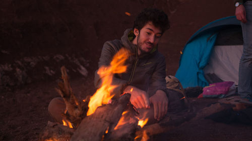 Young man sitting on fire at night