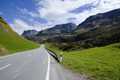 Scenic view of road by mountains against sky