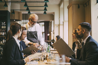 Waiter showing menu to business people in restaurant