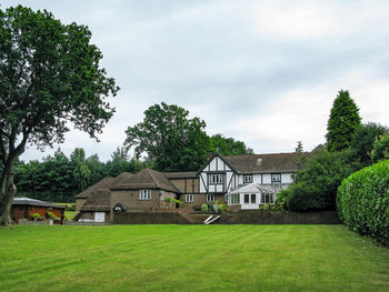 Trees and houses on field against sky
