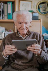 Smiling senior man using digital tablet at home