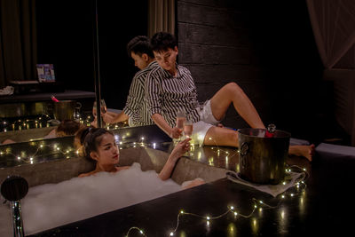 Man toasting champagne flutes with girlfriend in bathtub