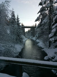 Footbridge over river against sky during winter