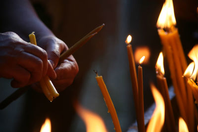 Cropped image of man lighting candles at temple