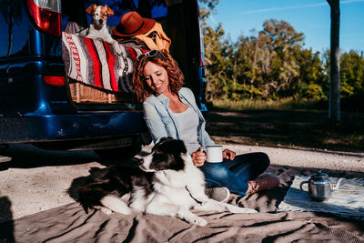 Smiling woman with dog sitting on blanket