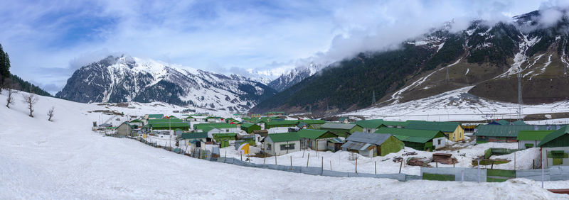 Panoramic view of buildings and snowcapped mountains against sky