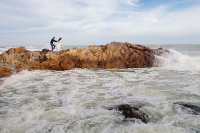 Couple walking on rock at beach