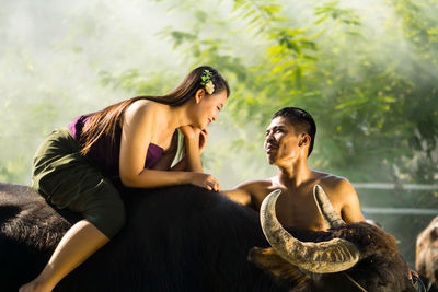 Loving boyfriend touching girlfriend sitting on buffalo
