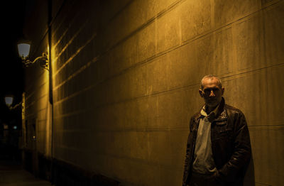 Adult man on street against brick wall with light of street lamp at night. shot in madrid, spain