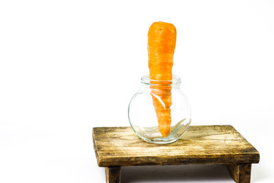 Close-up of orange glass on table against white background