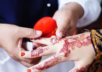 Close-up of bridegroom wearing ring to bride at wedding ceremony