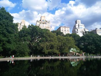 Scenic view of lake by trees and buildings against sky