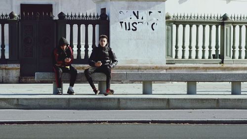 Full length portrait of woman standing against railing in city