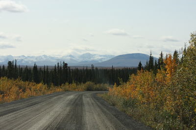 Road amidst trees against sky during autumn