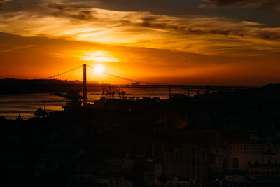 Sunset overlooking lisbon's baixa and 25 april bridge on the tagus river, portugal