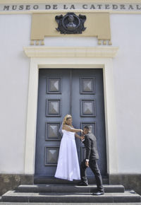 Woman leaning on door of building