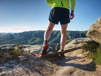 Rear view of man standing on mountain against sky