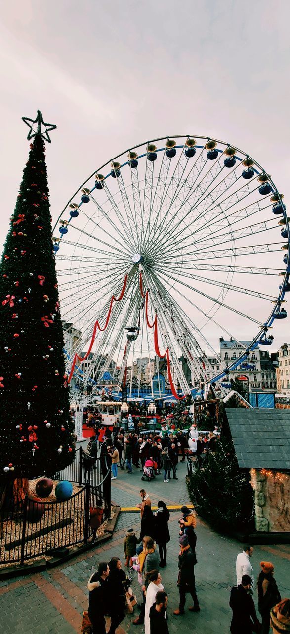 amusement park, group of people, amusement park ride, real people, ferris wheel, architecture, large group of people, crowd, arts culture and entertainment, sky, built structure, men, leisure activity, women, lifestyles, building exterior, nature, adult, city, travel destinations, outdoors, fairground