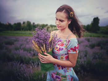 Young woman standing on field against sky