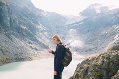 Young woman looking at phone with mountain lake seen below