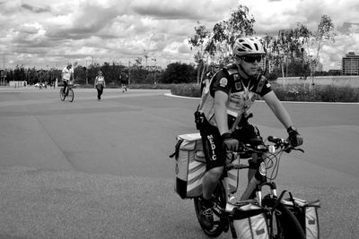 Man riding motorcycle on road against cloudy sky