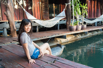 Portrait of smiling young woman sitting at lakeshore