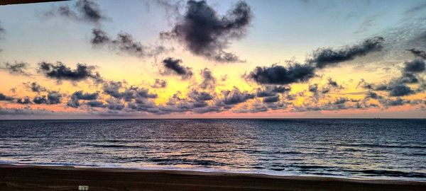 Scenic view of sea against dramatic sky during sunset