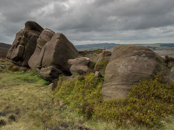 Rock formations on landscape against cloudy sky