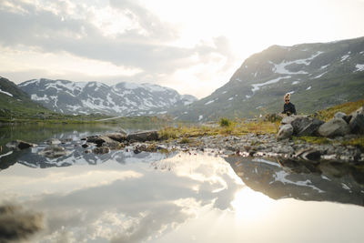 Woman sitting at lake in mountains