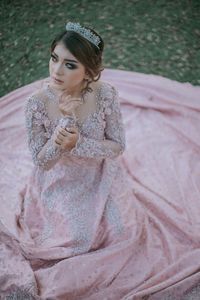 Beautiful woman in dress sitting on field