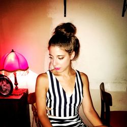 Young woman looking away while sitting on wall at home