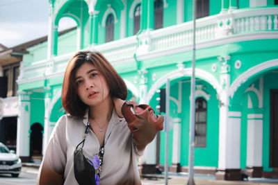 Portrait of beautiful woman standing against building