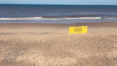 Text on beach by sea against sky