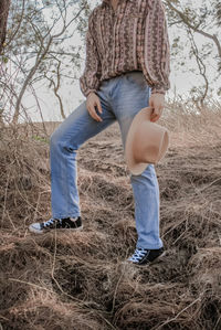 Low section of man standing on field against trees