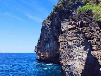 Rock formation by sea against blue sky