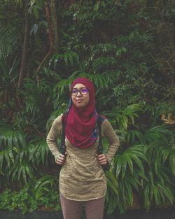 Woman in hijab standing against plants