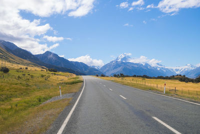 Road leading towards mountains against sky