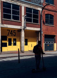 Rear view of man walking on street against building