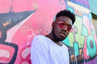 Young man wearing sunglasses against wall