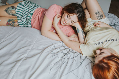 Young female girlfriends in pajamas relaxing on bed in bedroom