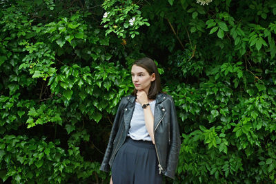 Woman in jacket standing against trees