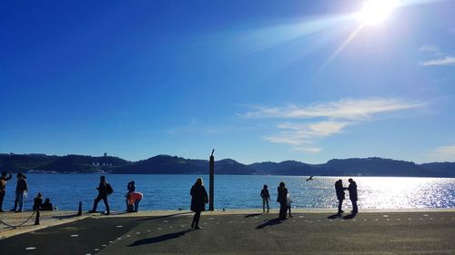 People on sea against blue sky